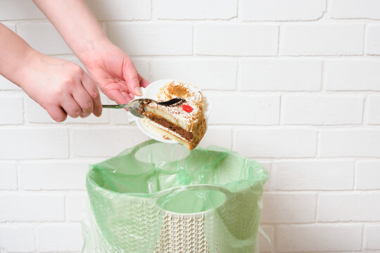 Female Hands Throw The Leftover Cake Into The Trash Can