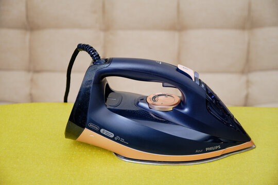 Philips Azur dark blue iron and an ironing board, close-up - Moscow, Russia, November 01, 2021