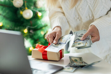 Young woman counting cash money for Christmas or new year present at home
