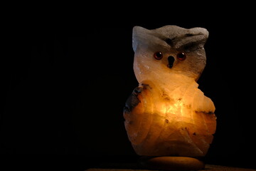 night light lamp lantern salt owl with warm yellow light inside on black background