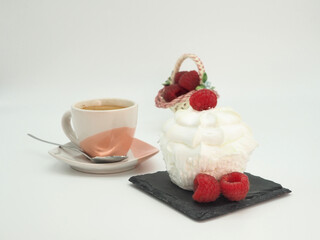 A cup of coffee, a cake and a raspberry basket. On white background