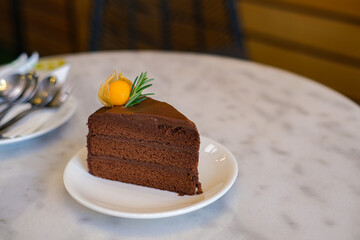 Triangle shape slices piece of dark chocolate fudge cake on white plate in café, Homemade bakery concept for birthday cake or valentine dessert.