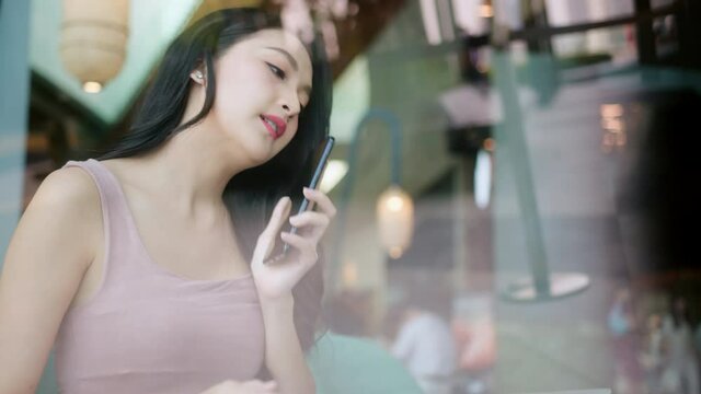 young attractive asian female wear casual cloth hand use smartphone and laptop device comminication social contact in cafe restaruant sit at counter next to big window daylight