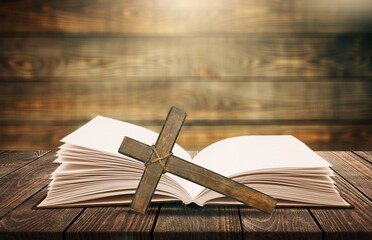 Dramatic bright light beam shining on an old bible with a rosary laying in front of it.