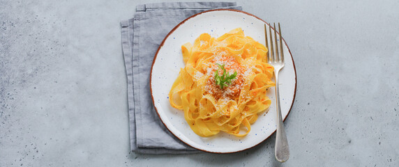 Fettuccine pasta with traditional Italian Passat sauce and parmesan cheese in light plate on old gray concrete background. Top view.