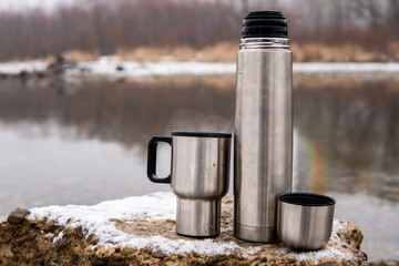 thermos with a thermo mug on the river bank
