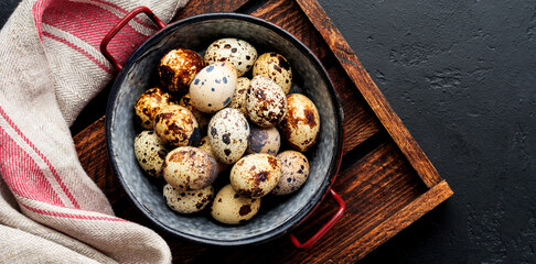 Quail eggs in metal plate on dark old background. Rustic style. Top view