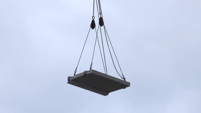 Hoisting construction works with tower crane during erection multistory building.  Close up of a crane hook lifting a heavy load.