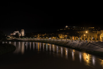 Fototapeta na wymiar City landscape with the illuminated streets along the bank of the Adige river at night, Verona, Veneto Region, Italy