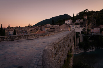 View of the historical medieval bridge of Nyons (Pont Roman) over the river Eygues and the old town buildings at sunrise, Département Drôme, Rhône-Alpes, France