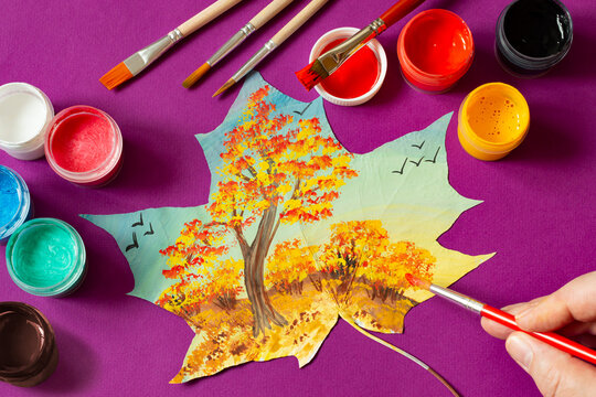 Landscape with autumn trees hand-painted on dry maple leaf