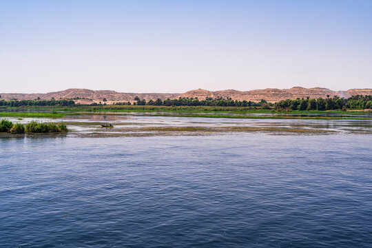 Navigating the river Nile with views of the shore, part oasis, part desert. Photograph taken in Aswan, Egypt. 