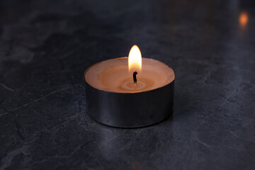 Fototapeta na wymiar One burning candle on the table closeup