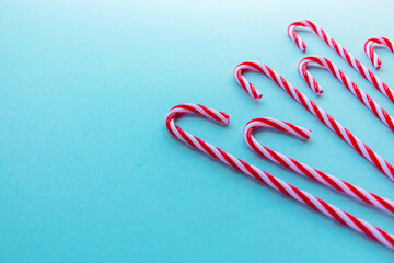 Candy canes on light blue background. Holiday sweets. Happy New Year and Merry Christmas theme. Flat lay, top view, copy space.
