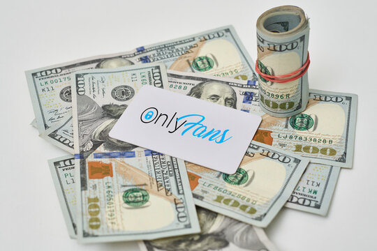 Tashkent, Uzbekistan - 22 November, 2021: Pile of us dollars and Onlyfans card. Onlyfans logo and cash money. Symbol of buying subscription on adults content subscription service, or earning money