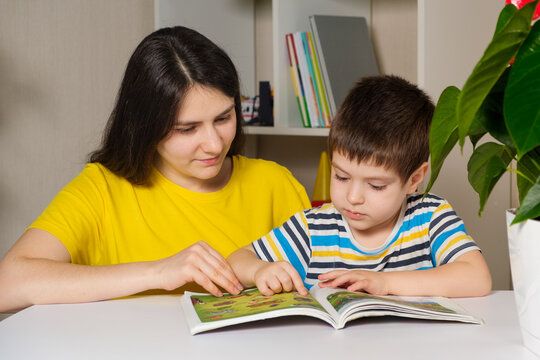 Mother and son read the book, look at the pictures on the pages. Leisure for children, spending time with parents.