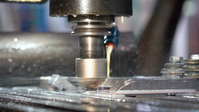 CNC Milling Machine Tool Cutting Steel - Zoom Out Shot.  Closeup Shot of a CNC Machine Processing A Piece Of Metal. Milling Tool Cooling By Coolant Emulsion.