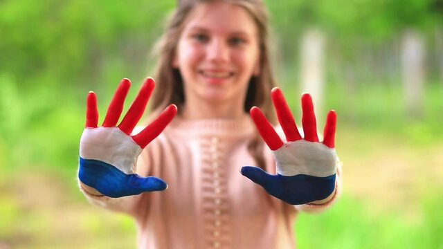 Teenager girl waving greeting with hands painted in Mongolia flag color. Focus on hands. July 10 National Flag Day. Mongolian memorial holiday 29th of December 