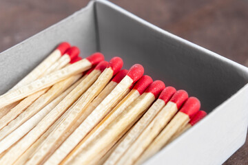 Full open box of matches with red sulfur heads on wooden background. Macro.