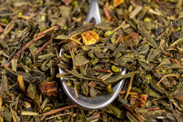 A full teaspoon of dried green hemp tea leaves in a heap. Natural legal marijuana drink