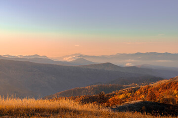 Sunrise at a village called Ravensca in Romania with distant mountains covered with fog