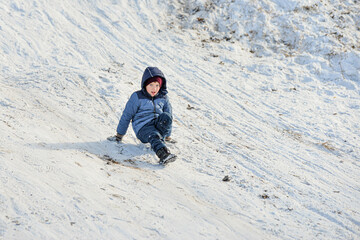 Fototapeta na wymiar The boy is rolling in the snow in winter.