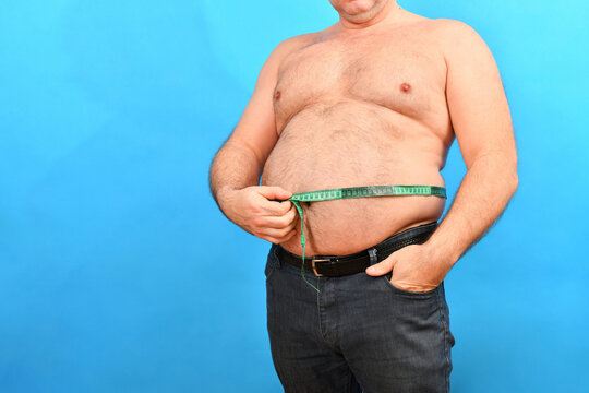 A man in jeans measures a large fat waist with a green centimeter.