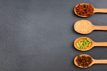 Spices and cane sugar on black background, top view with copy space