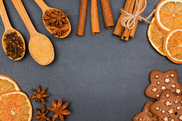 Spices, dried orange slices and cookies on black background. Baking background with copy spac