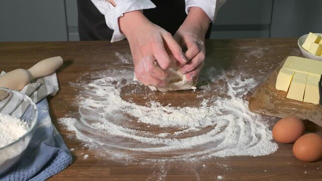 The cook kneads the baking dough on the table with the ingredients