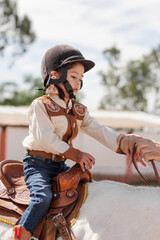 Cute girl ridding a horse in cowgirl clothes