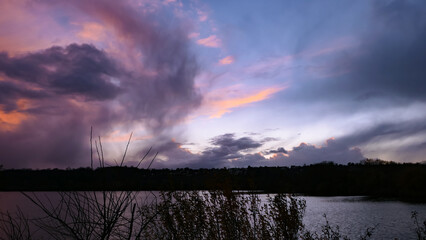 Dramatic sky over the water. Stormy landscape with dark clouds. View on a lake or sea at sunset or sunrise.
