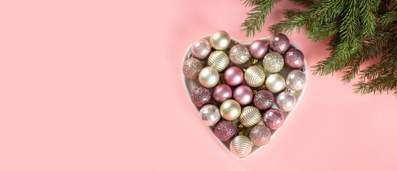 Pink background with fir tree and Christmas toys for Christmas design. Merry christmas and Happy Holidays. Banner. Flat lay, top view and place for text.