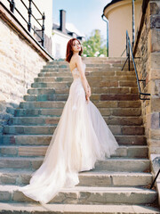 Pink bridal gown. Beautiful bride in pink wedding dress with long train on stone stairs....