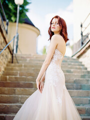 Pink wedding dress. Beautiful bride in pink wedding dress with long train on stone stairs....