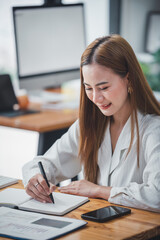 Asian woman sitting at a desk working in the office use a computer, laptop