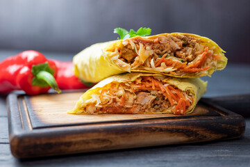 delicious fast food shawarma in pita bread with vegetables and pork and veal on a wooden board