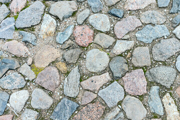 a fragment of a cobblestone pavement of different sizes and shapes. Close-up. Weathered surface