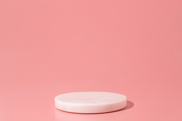 White marble podium on the pink background. Podium for product, cosmetic presentation. Creative mock up. Pedestal or platform for beauty products.