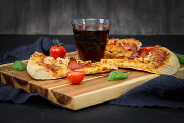 A glass with Coca Cola, three slices of pizza on a cutting board .