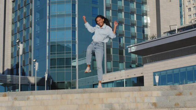Active happy carefree girl winner young stylish woman model brunette glad dancer dancing having fun in city on building background flying hair dance outdoors junping jump sing rejoice victory holiday