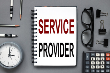SERVICE PROVIDER. text on white paper. the inscription on the notebook. business concept. notepad on a gray background. glasses, pen, pencil, watch, calculator