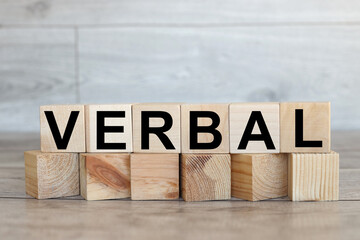 VERBAL. wooden cubes on a wooden background. three wood blocks