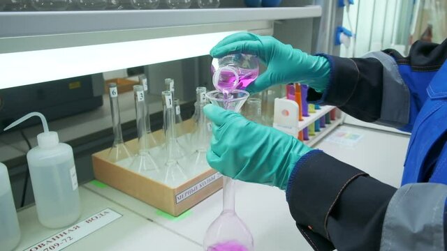 Chemistry concept. Clip. A man in gloves who tests a pink liquid for an experiment.