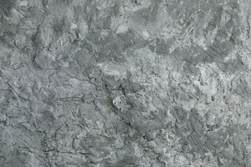 Grey textured clay wall design with cracks and imperfections. Wall design ideas in contemporary interior.