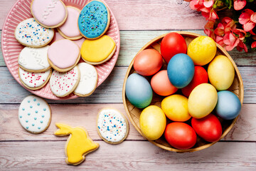 Easter cookies and colorful eggs on pink wooden background