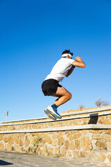 Young caucasian man exercising in the park jumping a step