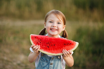 Happy child girl with big slice of watermelon on summer day outdoors