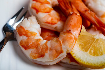 Close up of fresh shrimp on a plate with forks and lemon slice