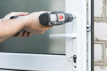 Handyman check door lock with screw gun in front door. Lock checking close up for operability.